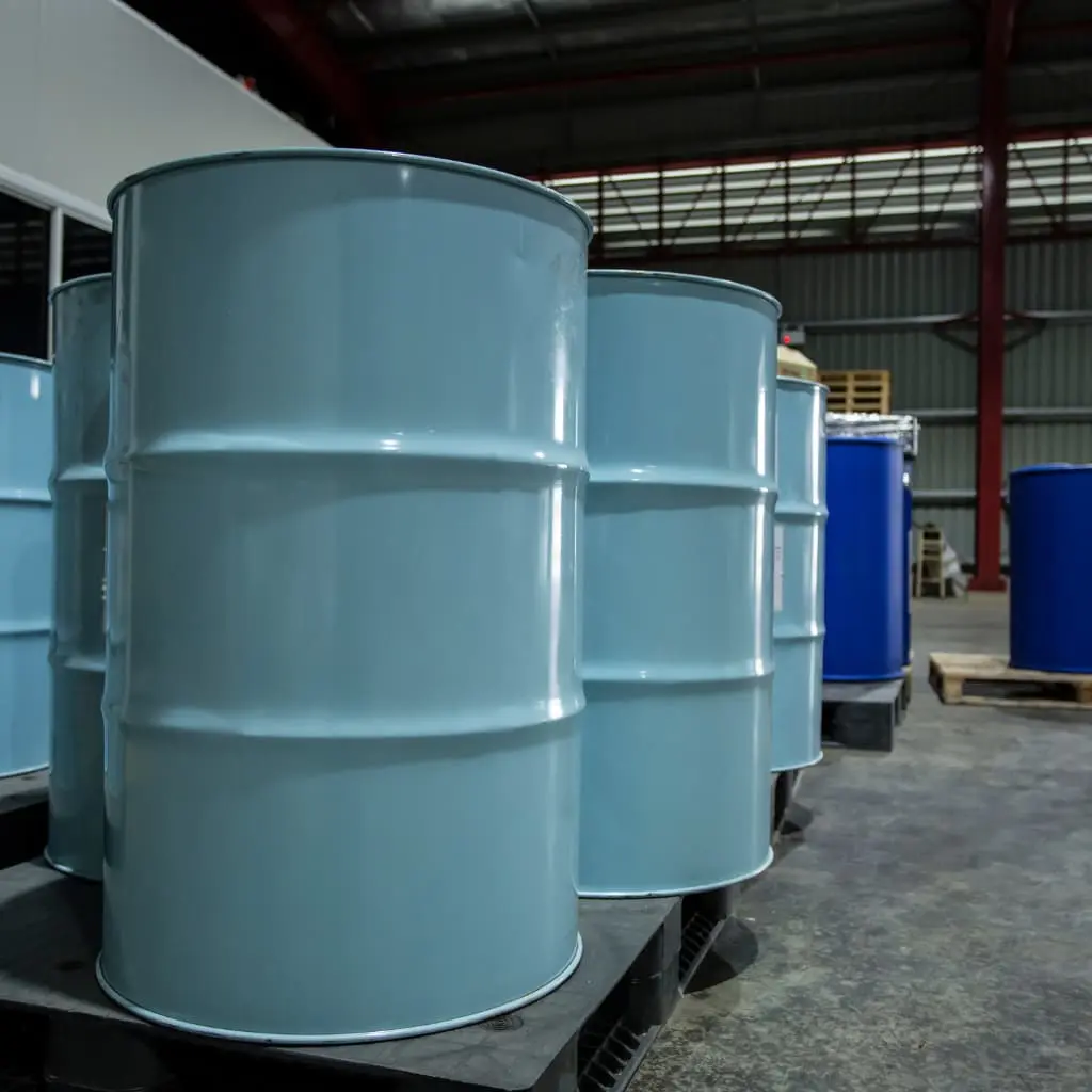 Bidones metálicos y plásticos con productos químicos almacenados en zona industrial