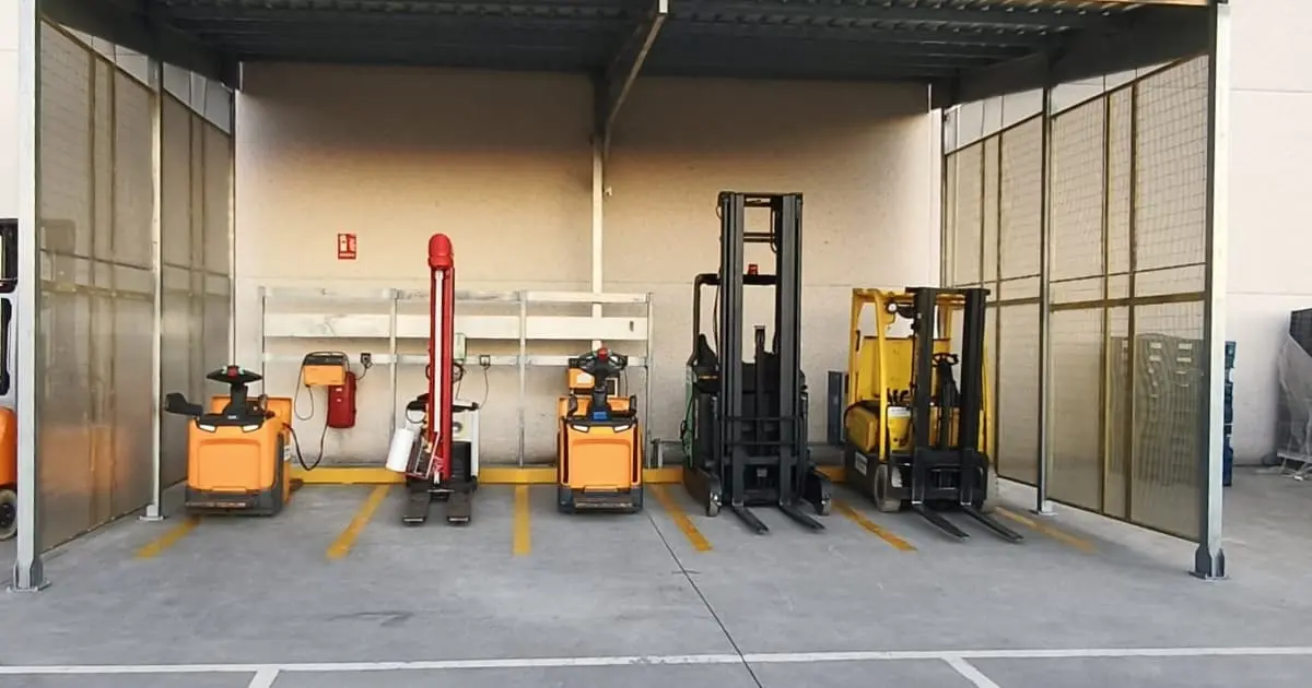 Sala de carga de baterías exterior con ventilación natural, cubierta metálica y plazas señalizadas para carretillas eléctricas de Papa John's